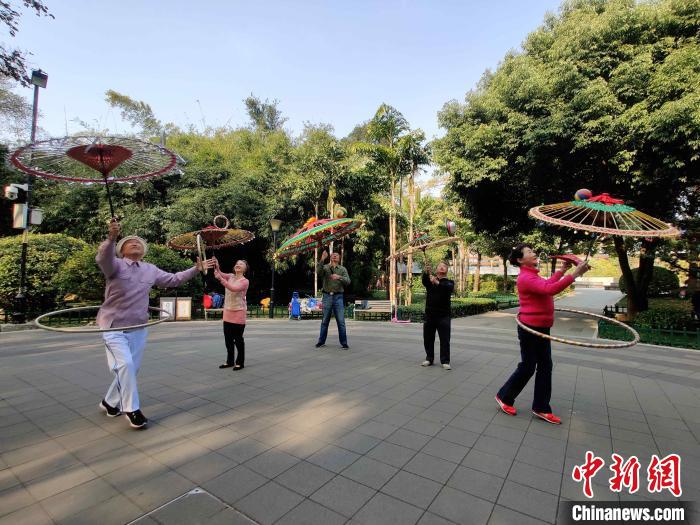 福州金瓯民间伞技队队员正在福州市温泉公园排练,吸引众人围观。 叶秋云 摄 福州金瓯民间伞技队队员正在福州市温泉公园排练,吸引众人围观。 叶秋云 摄